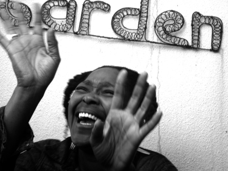 Photo of woman laughing and holding hands up behind a wire art sign that spells out "arden" behind it